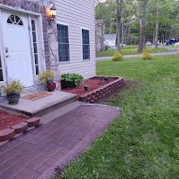 There is a brick walkway leading to the front door of a house.