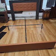 A bed is sitting on a wooden floor in a bedroom.