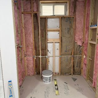 A bathroom under construction with insulation and a window.