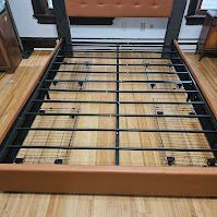 A bed frame is sitting on top of a wooden floor in a bedroom.