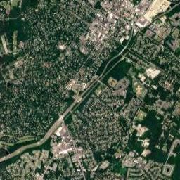 Satellite view of a suburban area featuring residential streets, green spaces, and a highway running diagonally.