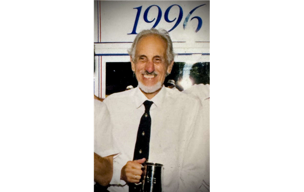 A man holding a trophy in front of a sign that says 1996