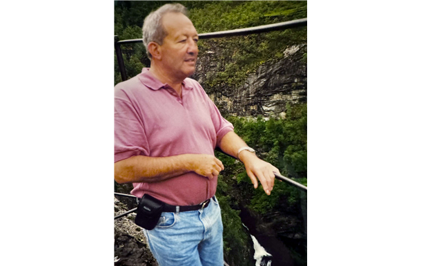 A man in a pink shirt is standing on a bridge