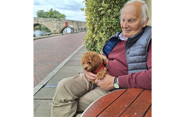 A man is sitting at a table holding a small dog