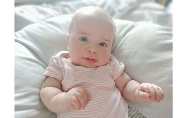 A baby is laying on a pillow on a bed.