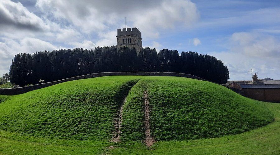 A large grassy hill with a church in the background