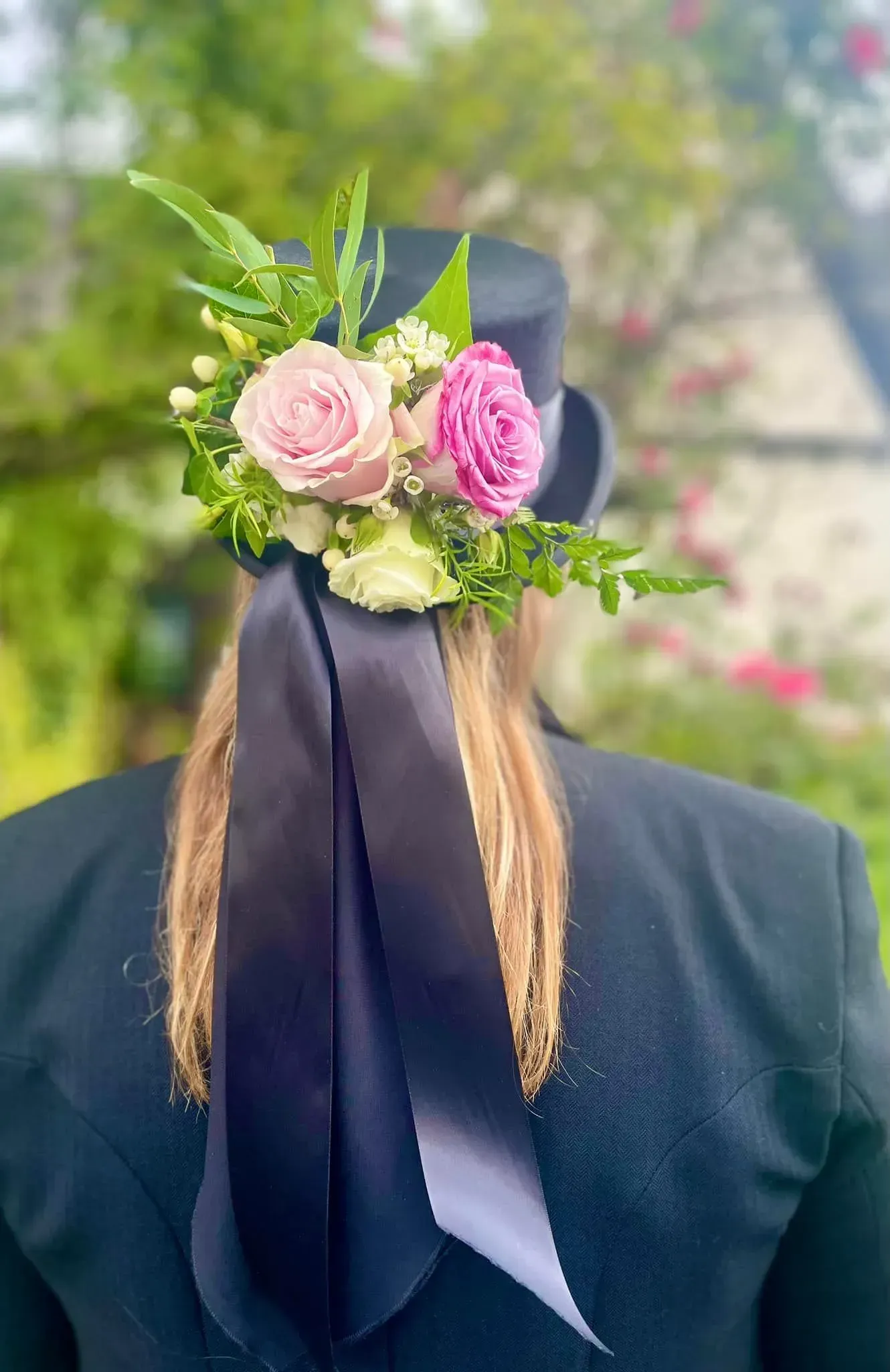 A woman wearing a top hat with flowers in her hair