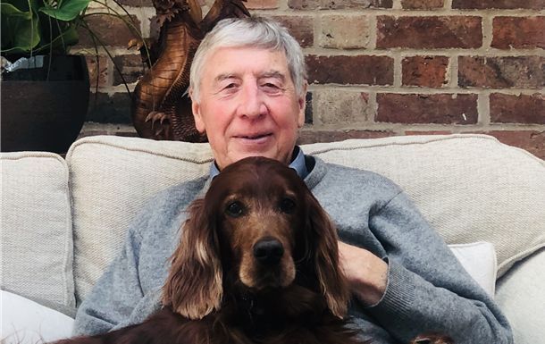 A man is sitting on a couch with a dog on his lap.