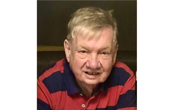 A man in a red and blue striped shirt is sitting on a couch.