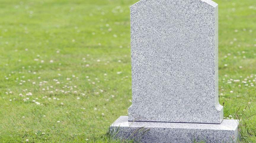 A gravestone in the middle of a grassy field