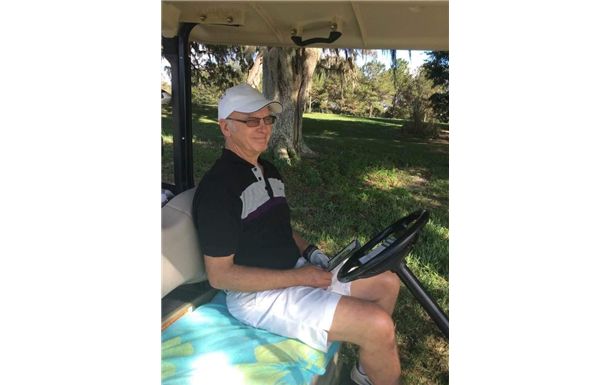 A man is sitting in a golf cart on a golf course.