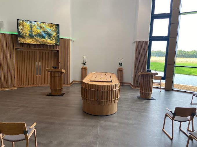 A room with a table , chairs , podiums and a television on the wall.