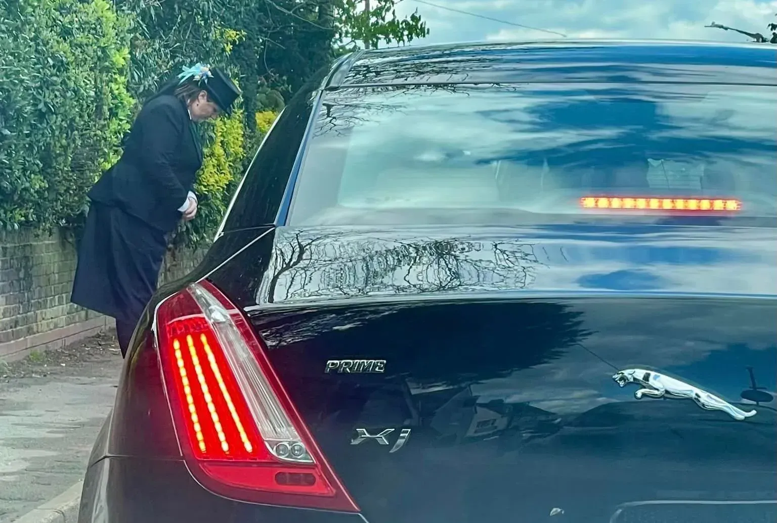 A woman is standing next to a black car.