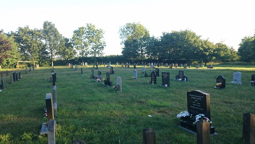 A cemetery with many graves and trees in the background