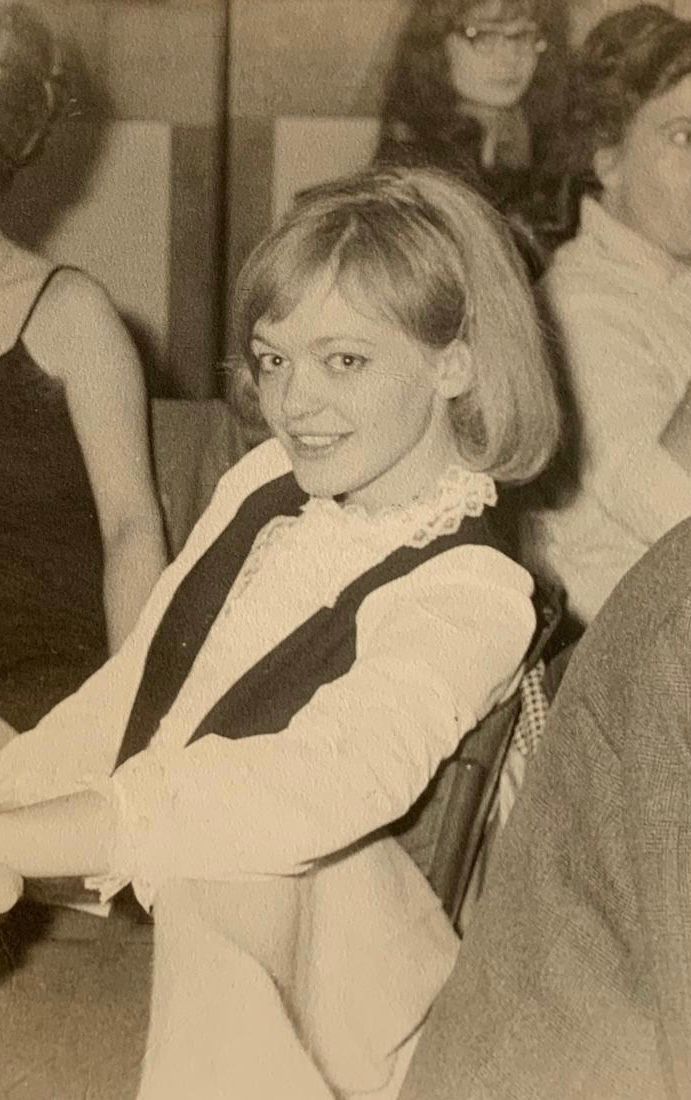 A young woman is sitting in a chair in a black and white photo.