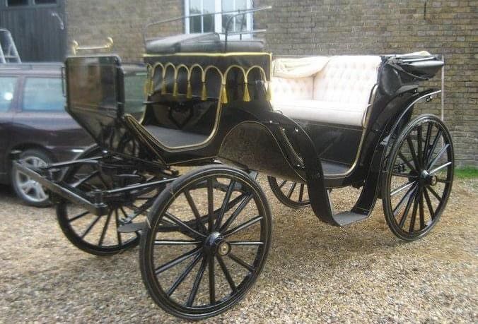 A horse drawn carriage is parked in front of a brick building