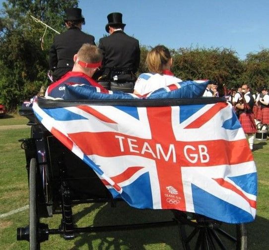 A team gb flag is draped over the back of a horse drawn carriage