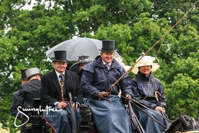 A group of men in top hats are riding in a horse drawn carriage.