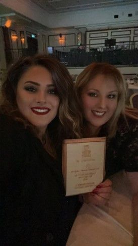 Two women are posing for a picture in a restaurant while holding a menu.