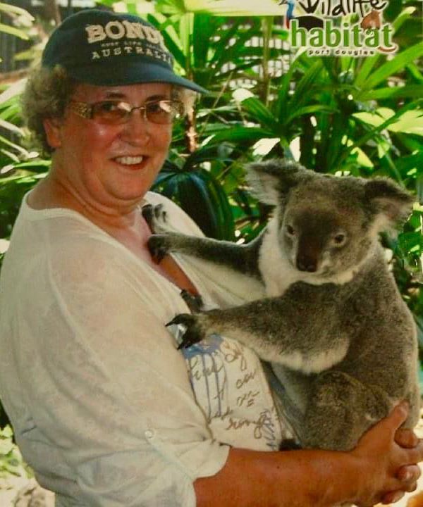 A woman holding a koala bear wearing a hat that says bond australia