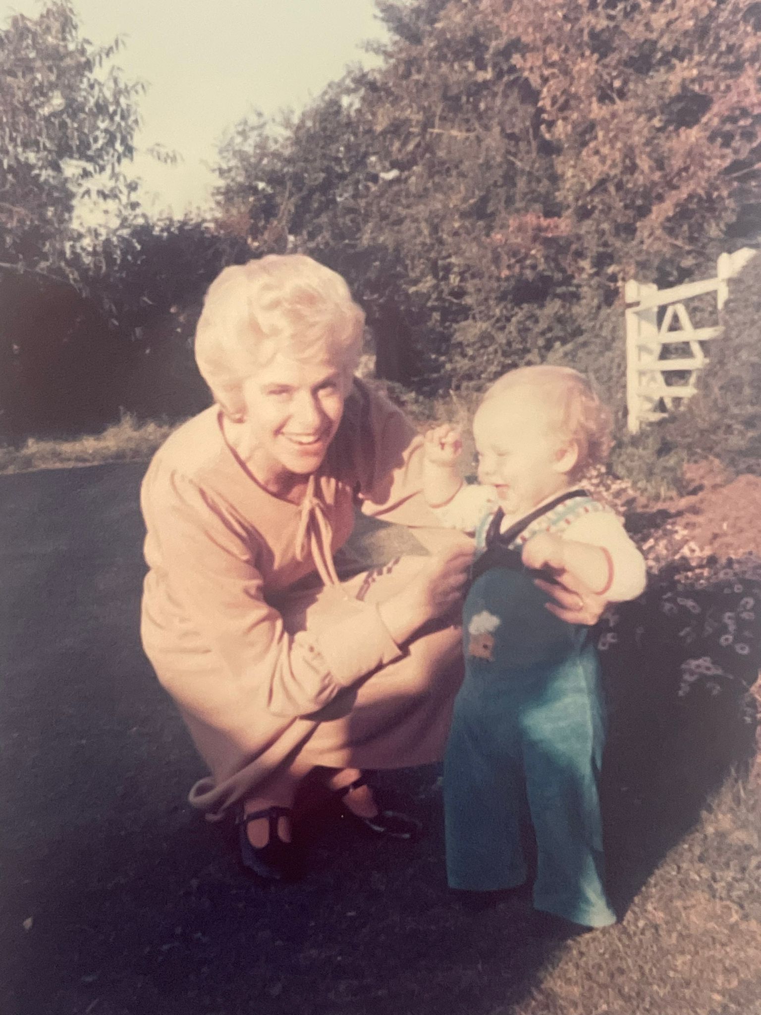 A woman is kneeling down holding a baby in her arms