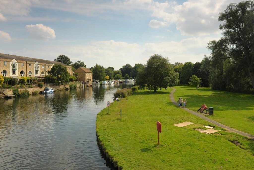 A river runs through a St Neots park with houses in the background