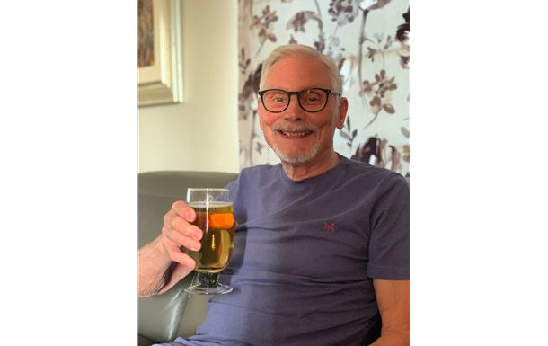 A man is sitting on a couch holding a glass of beer.