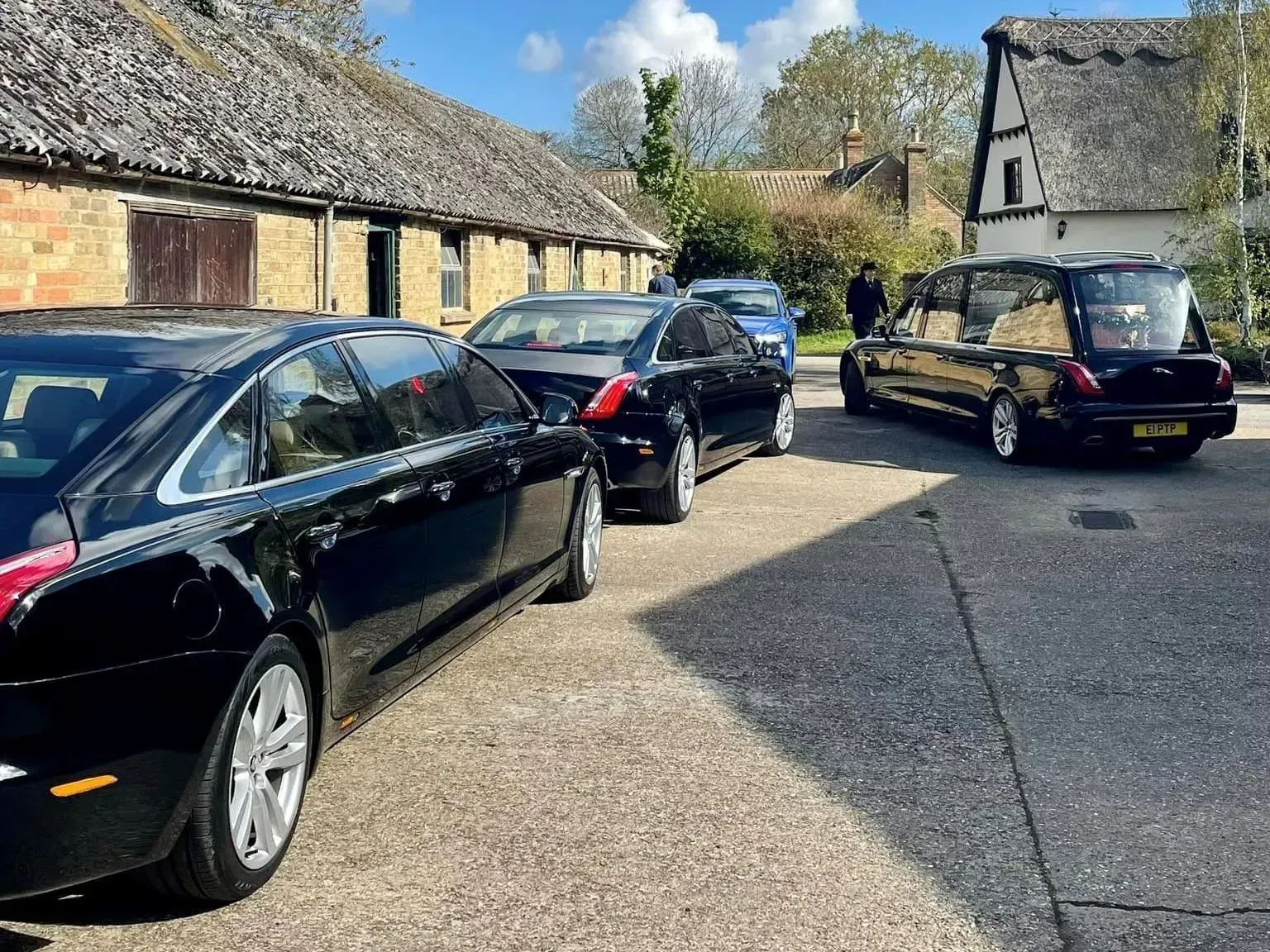 Three black cars are parked in a driveway in front of a building.