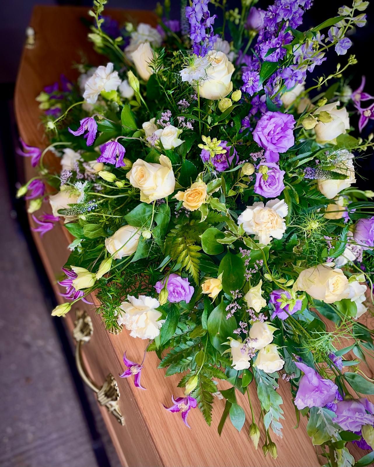 A coffin with purple and white flowers on it