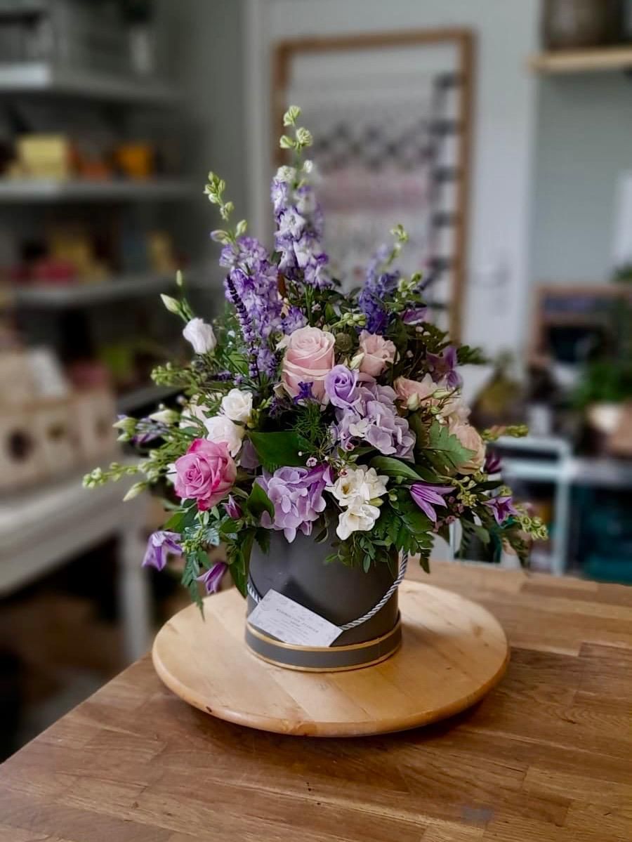 A vase filled with purple and pink flowers is sitting on a wooden table.