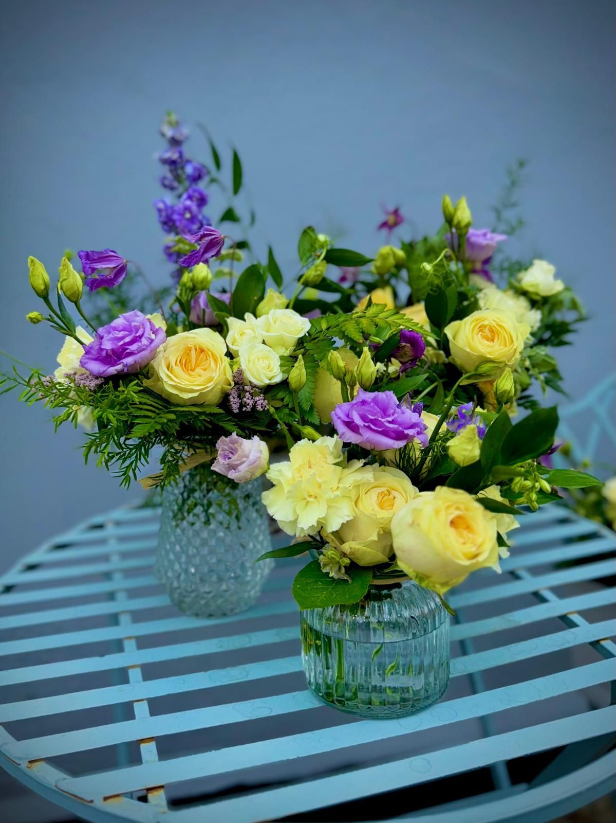 Two vases filled with yellow and purple flowers on a table