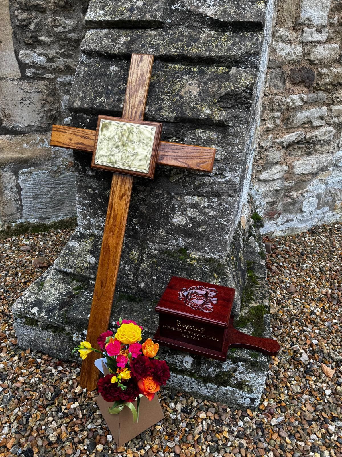 A wooden coffin filled with flowers is in a funeral car.