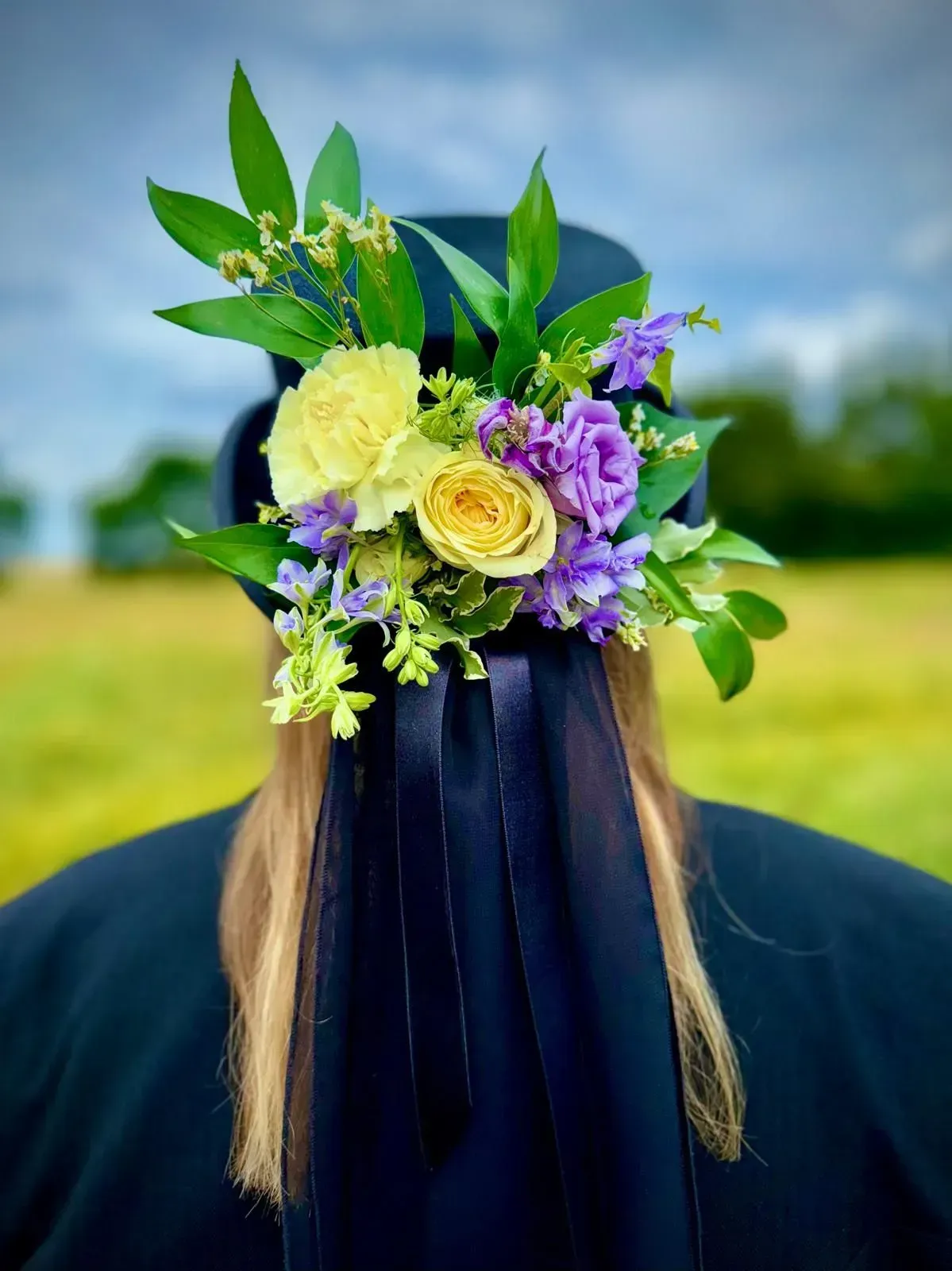 A woman wearing a graduation cap with flowers in her hair