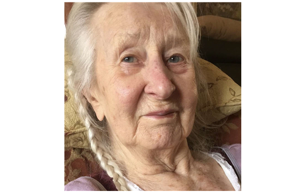 Elderly woman with gray braided hair, gazing at the camera.