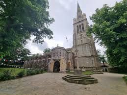 A large church with a clock tower in the middle of a park surrounded by trees.