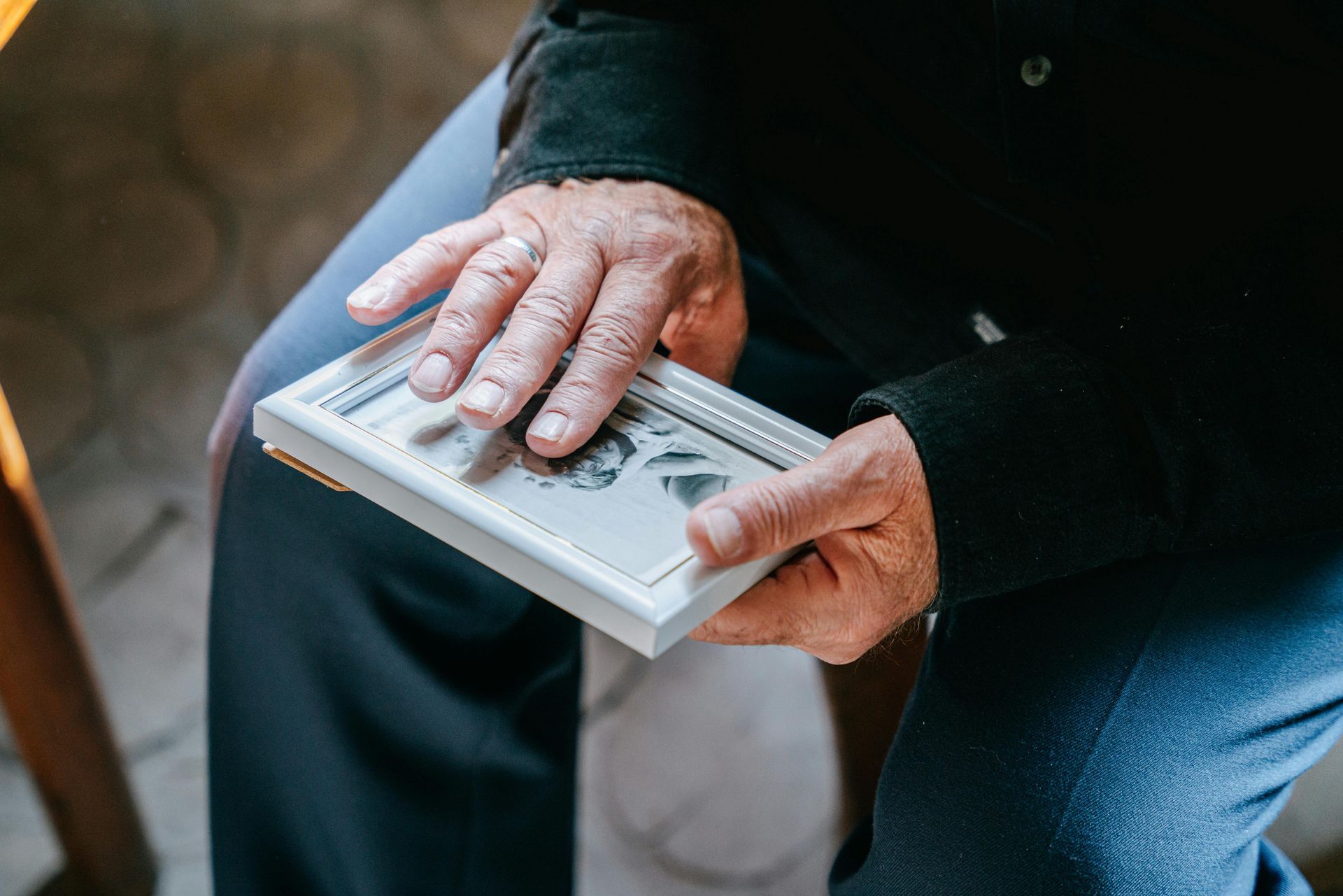Person holding framed black and white photo, resting on lap.