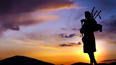 A silhouette of a man playing bagpipes at sunset