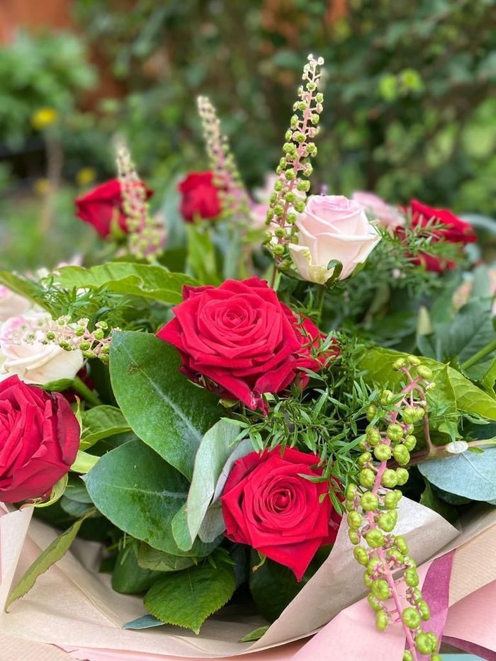 A close up of a bouquet of red and pink roses on a table.