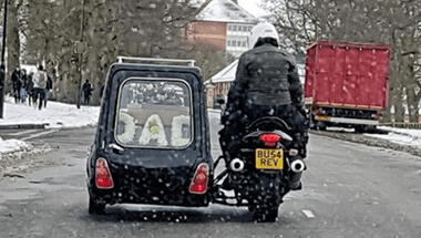 A man is riding a motorcycle next to a car that says dad on the back.