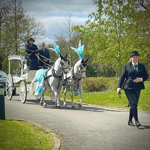 A horse drawn carriage is being pulled down a road by two horses.