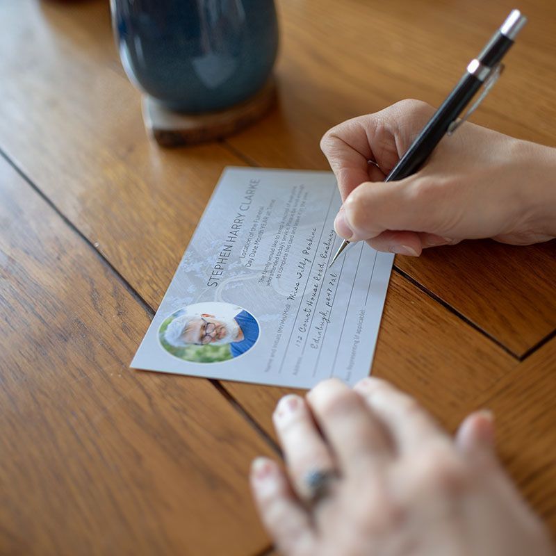 A person is writing on a piece of paper with a picture of a man on it