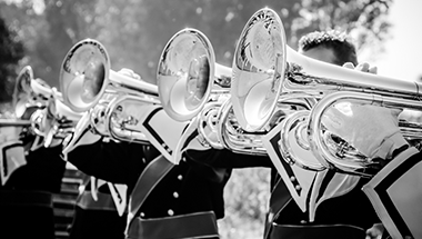 A black and white photo of a marching band playing trombones.