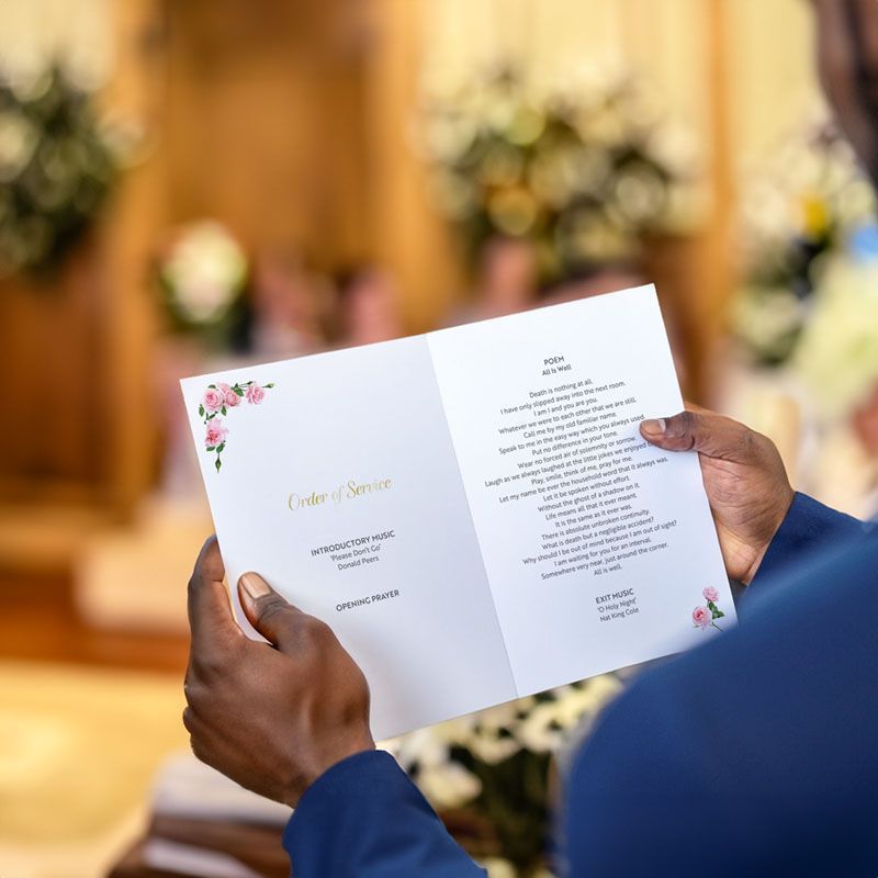 A man is holding a wedding program in his hands