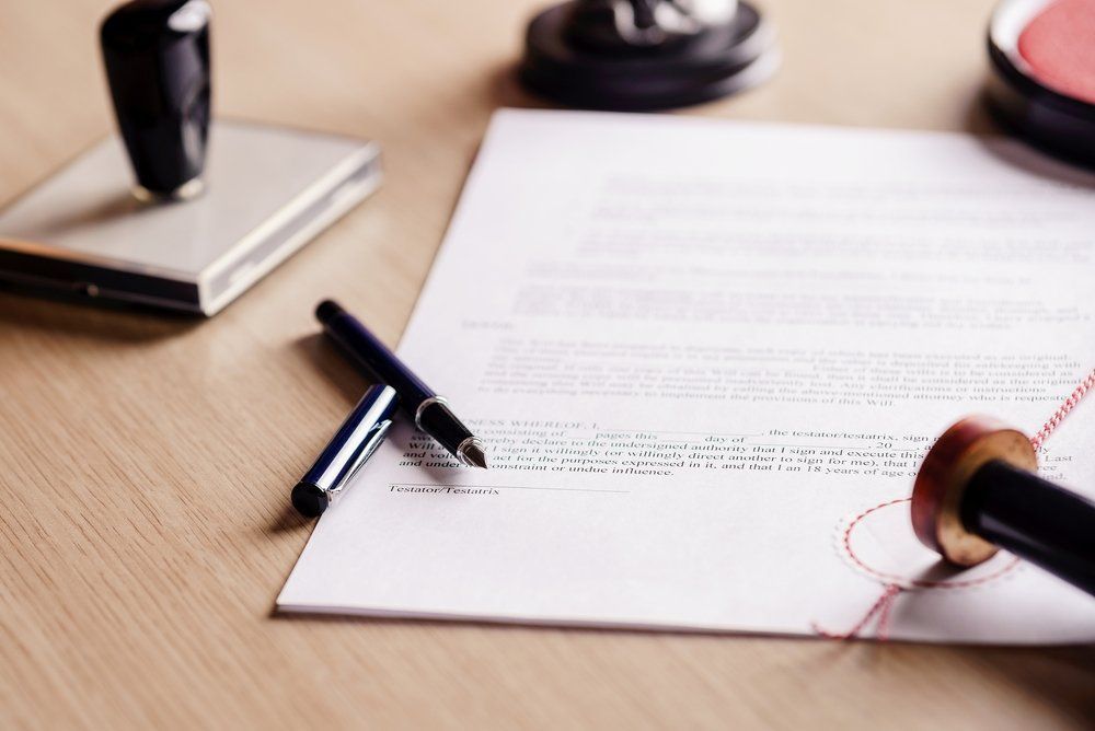 A person is signing a document with a stamp on it