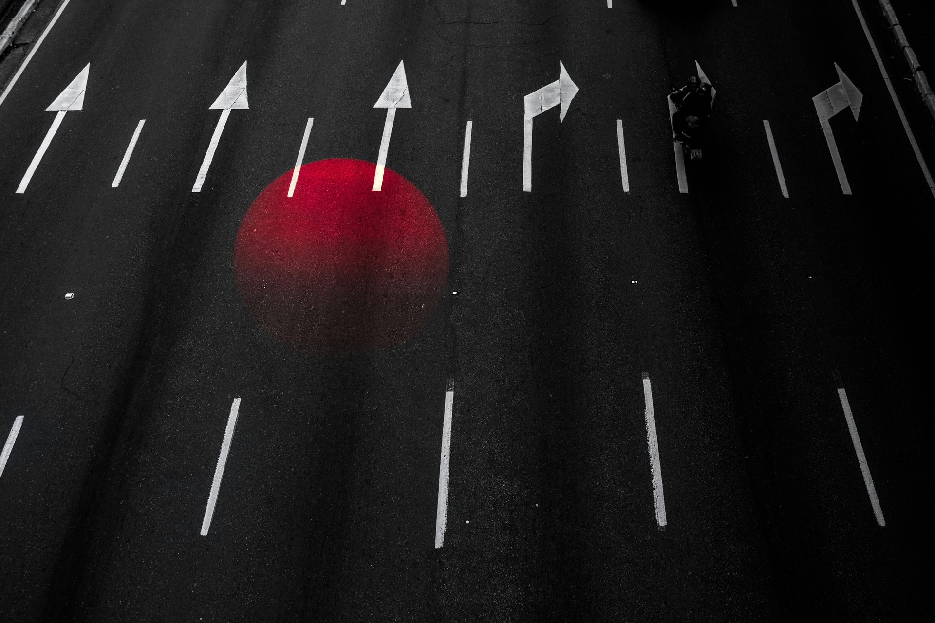 Road surface with white directional arrows, one red circle.