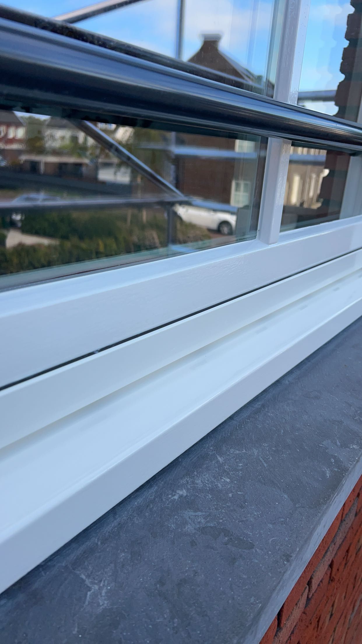 Een close-up van een witte vensterbank op een bakstenen muur.