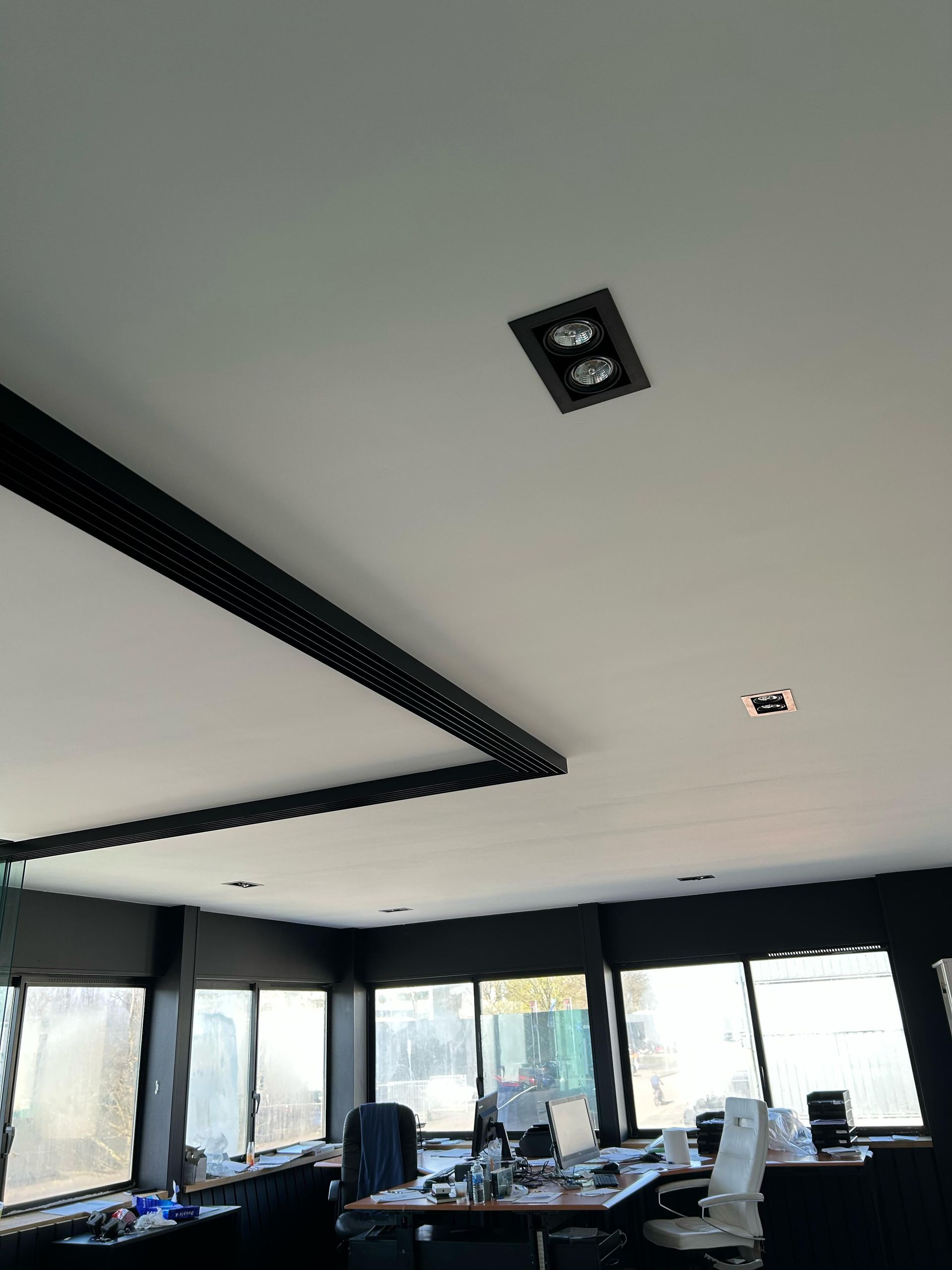 Een kamer met veel ramen en een wit plafond.