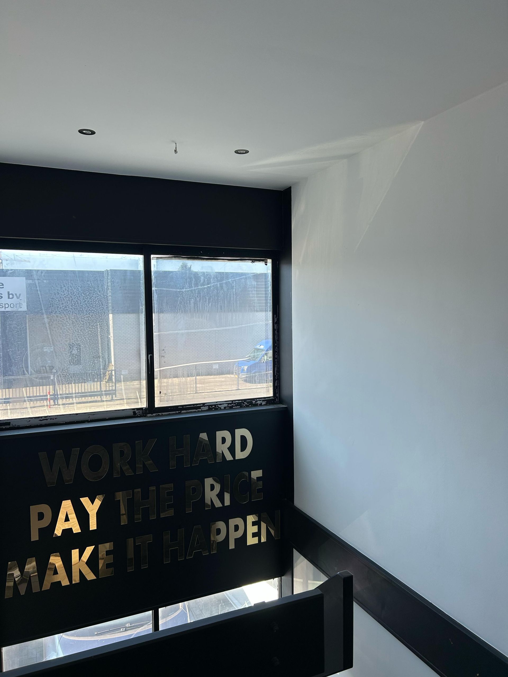 Een kamer met een bordje aan de muur waarop staat ``werk hard, betaal de prijs, maak het open''