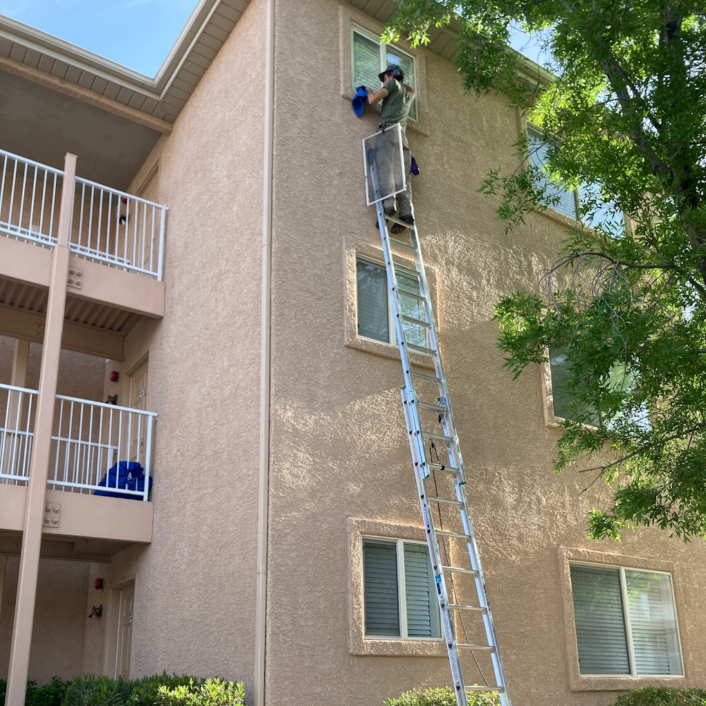 32 foot ladder leaning against an apartment building with Brandon from Closing Cleaners cleaning 3rd story windows