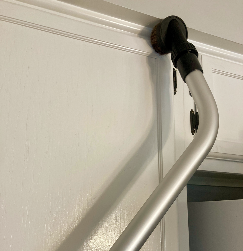 Closing Cleaners using a specialized horse hair brush attachment on metal pole detail vacuuming painted kitchen cabinets 